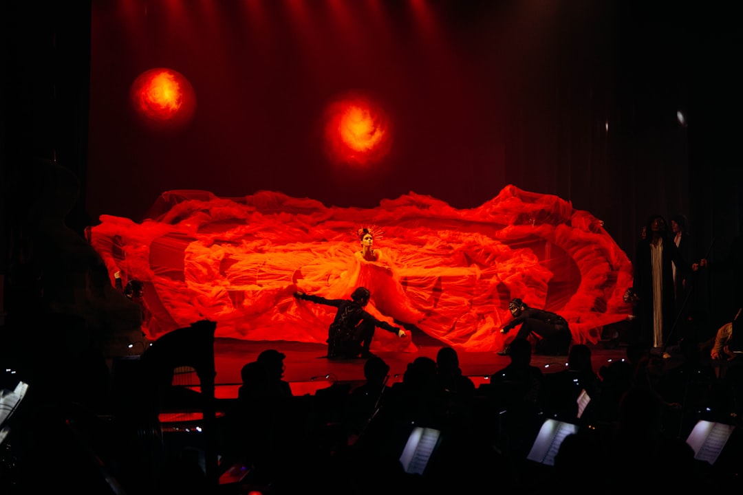 a person on a stage with a red curtain
