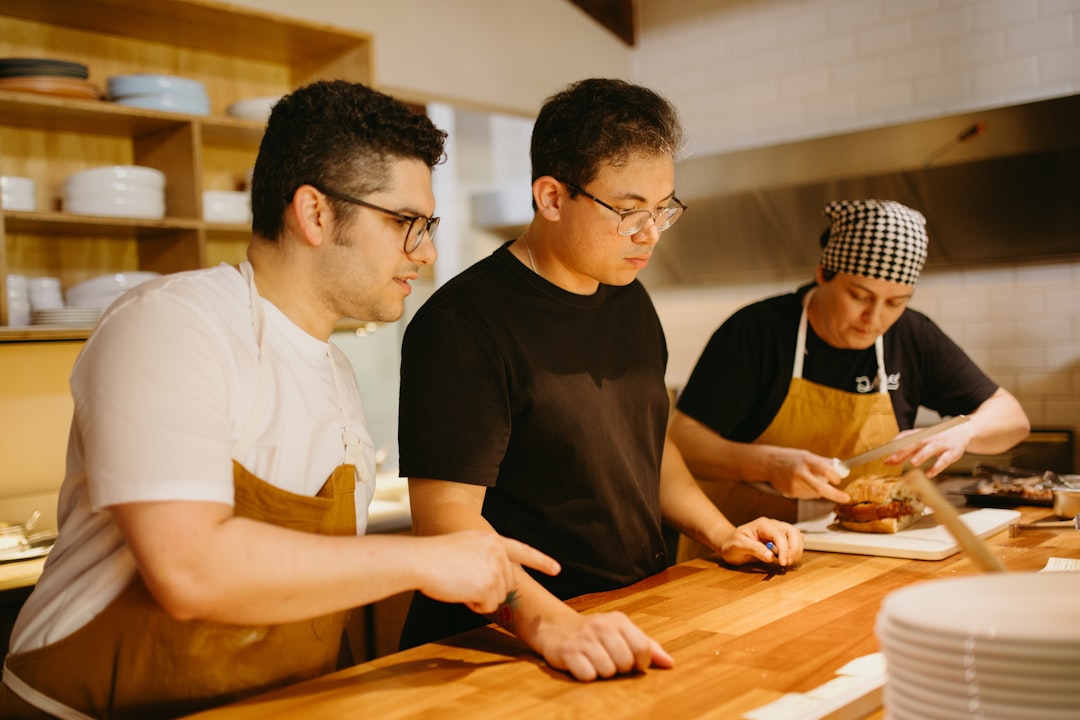 Three men in a kitchen preparing food on a cutting board