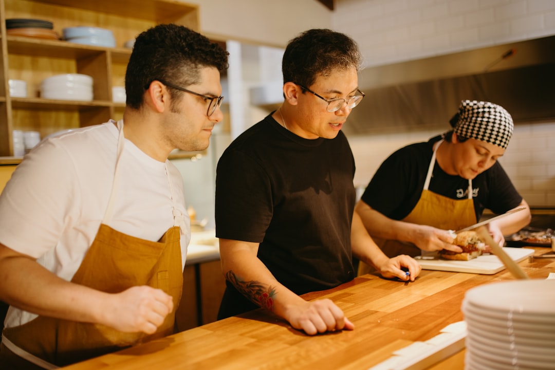 Three men in a kitchen preparing food on a cutting board