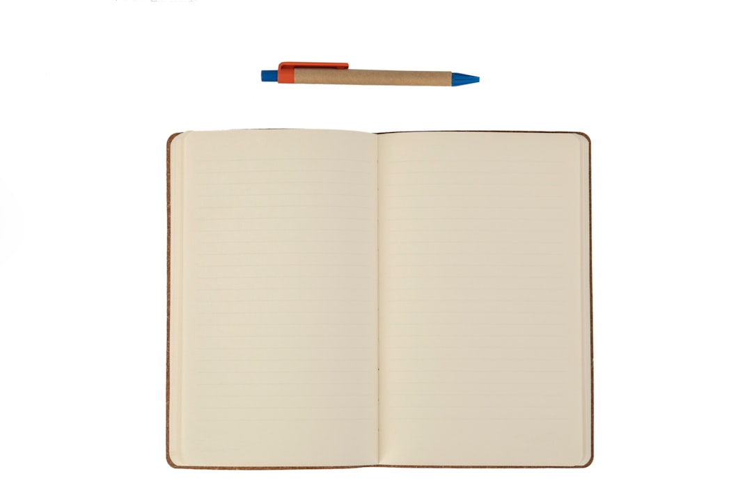 An open notebook with lined pages and a ballpoint pen above it